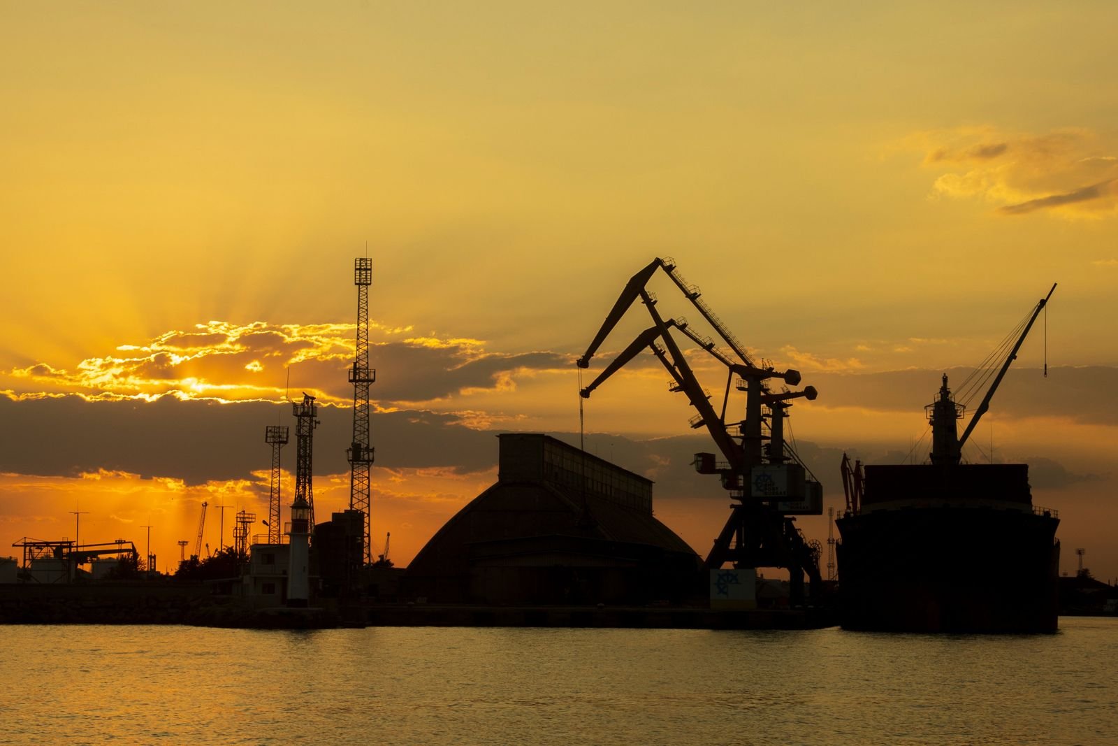 Bulk cargo terminal with cranes and stockpiles at sunset