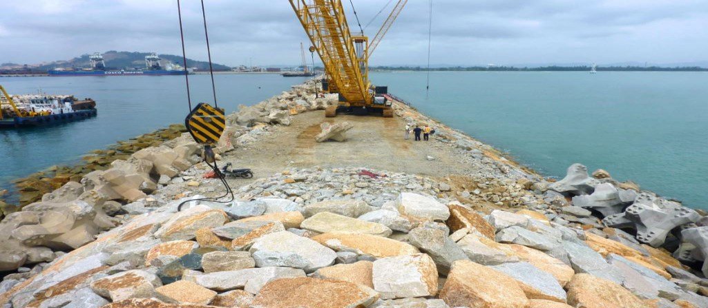 Crane discharging boulders on a jetty for a project